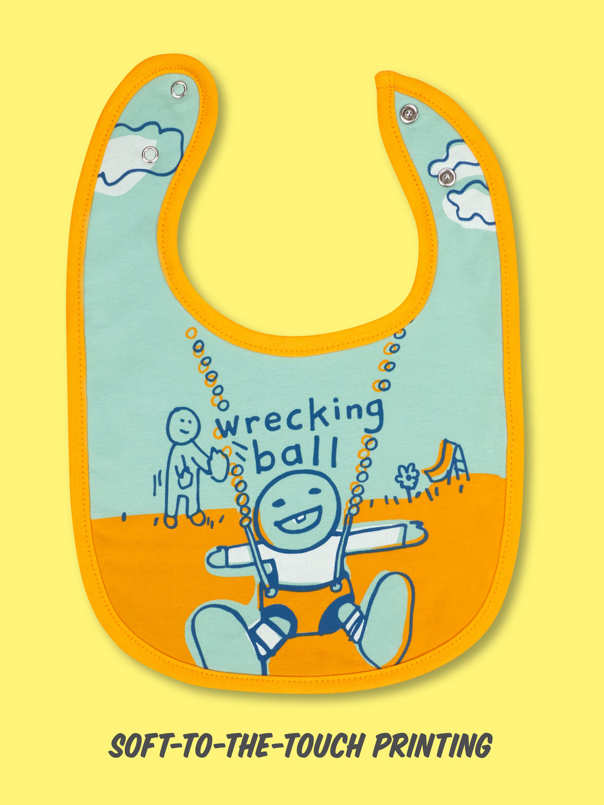 The Sweet Pea/ Wrecking Ball Baby Bib by Blue Q features a blue and orange design with playful playground art, “wrecking ball!” text, and is crafted from absorbent jersey with soft-to-the-touch printing for mess-free meals.