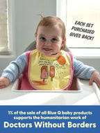 A smiling baby in a high chair wears a Blue Q "Tiny Little Dumpling/ Wanna Join Me For A Meltdown?" bib. Each sale helps support Doctors Without Borders.