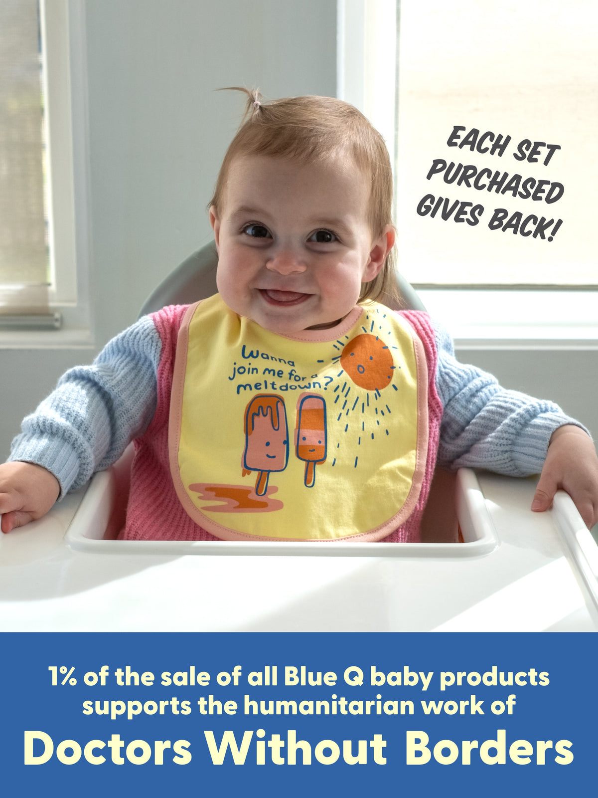 A smiling baby in a high chair wears a Blue Q "Tiny Little Dumpling/ Wanna Join Me For A Meltdown?" bib. Each sale helps support Doctors Without Borders.