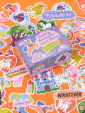 A purple Blue Q Overly Dramatic Unicorns Playtime Sticker Set box surrounded by various unicorn-themed stickers on an orange surface.
