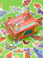 A Blue Q Some Of These Are Butterflies And Some Are Actually Moths Playtime Sticker Set featuring 47 vinyl butterfly and moth stickers surrounded by loose lepidopterans on a green background.