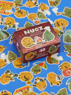 A Nugz Playtime Sticker Set box of 40 vinyl stickers featuring illustrated chicken nugget dippers and cannabis bud dabbers, surrounded by several individual stickers from the set on a bright blue background.