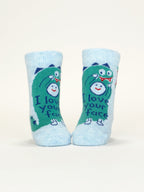 A pair of Blue Q “I Love Your Face/If You Drop Me I’ll Remember” baby socks, light blue with a green dinosaur design, made from OCS certified organic cotton. They stand upright against a plain white background.