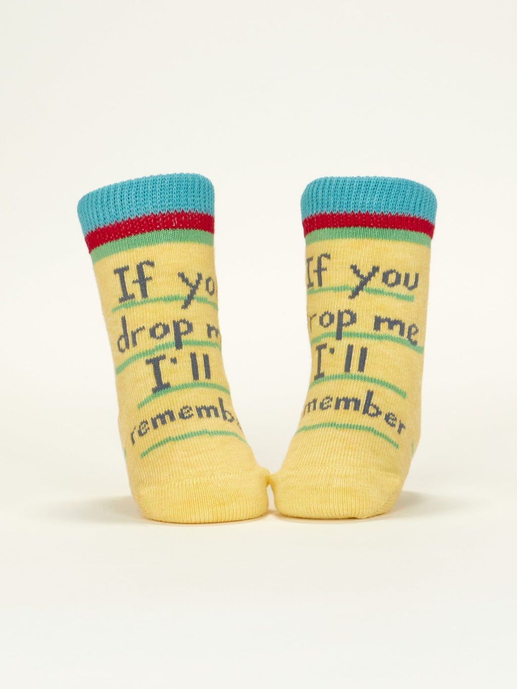 Blue Q’s “I Love Your Face/If You Drop Me I'll Remember” baby socks, made from OCS certified organic cotton, feature a yellow design with playful blue, red, and green accents—standing out on a plain light background.