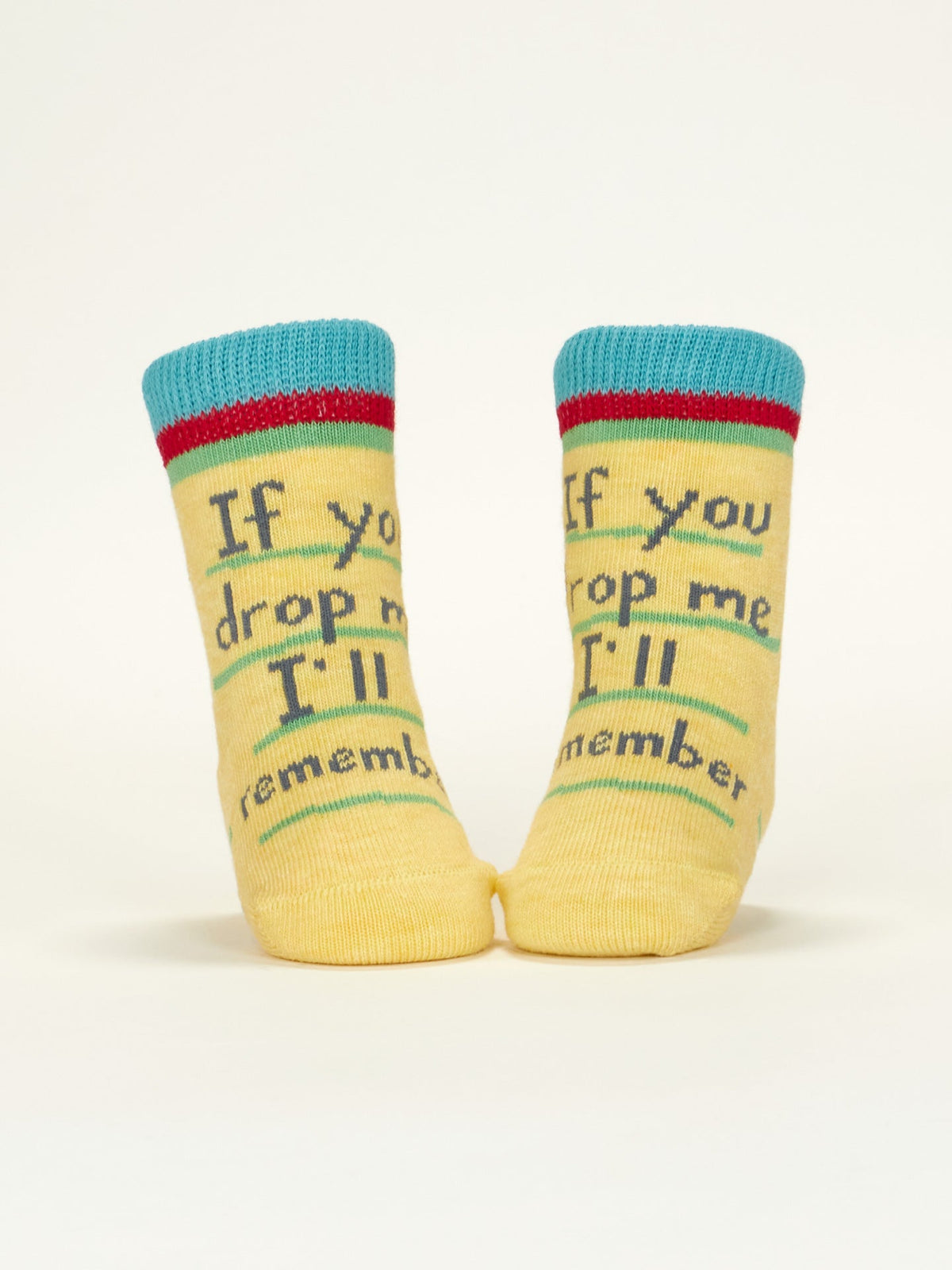 Blue Q’s “I Love Your Face/If You Drop Me I'll Remember” baby socks, made from OCS certified organic cotton, feature a yellow design with playful blue, red, and green accents—standing out on a plain light background.