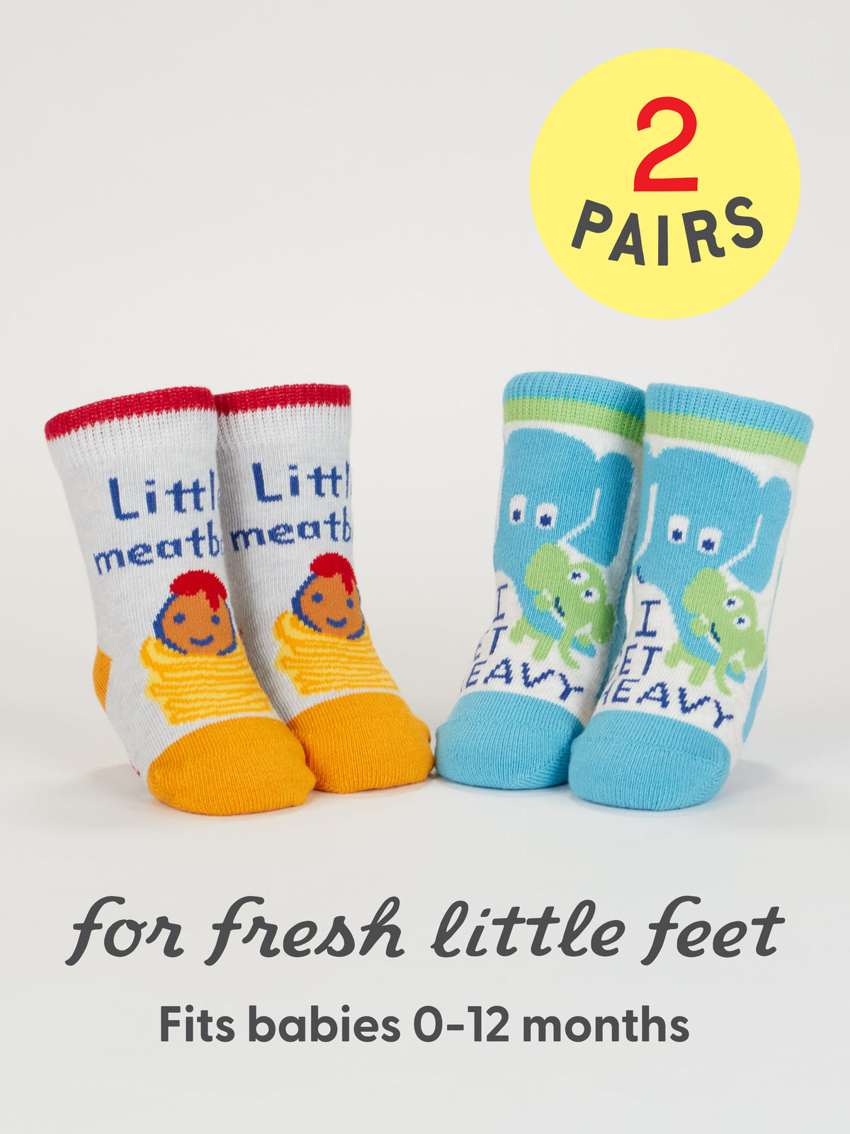 Blue Q’s Little Meatball/I Get Heavy Baby Socks: two pairs for 0-12 months, one with “cute meatballs” & caterpillar, the other with elephant & frog. Shown under a yellow “2 PAIRS” circle—perfect for fresh little feet.