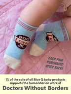 A baby sporting Blue Q’s Dog Lover Jr./ Itty Bitty Buddies organic cotton socks relaxes on a pink quilt, all set for playful adventures with their new buddies. With every pair purchased, 1% of Blue Q baby product sales supports Doctors Without Borders.