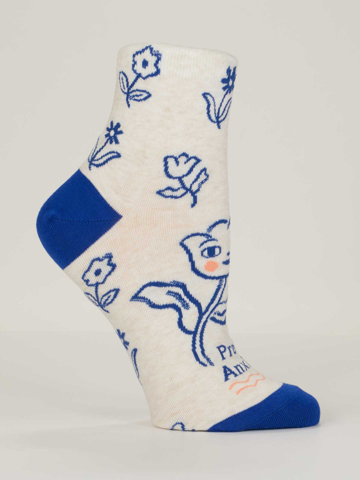 The Pretty Anxious W-Ankle Socks by Blue Q are cream-colored women’s socks in combed cotton, with blue toe and heel, blue floral line art, and a cartoon fox with a flower. Fits shoe size 5-10; partial small text near the toe.