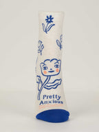 The Pretty Anxious W-Ankle Socks by Blue Q are white combed cotton for women (shoe size 5-10), with a blue toe, a smiling cartoon flower, and "Pretty Anxious" in blue and orange text below.